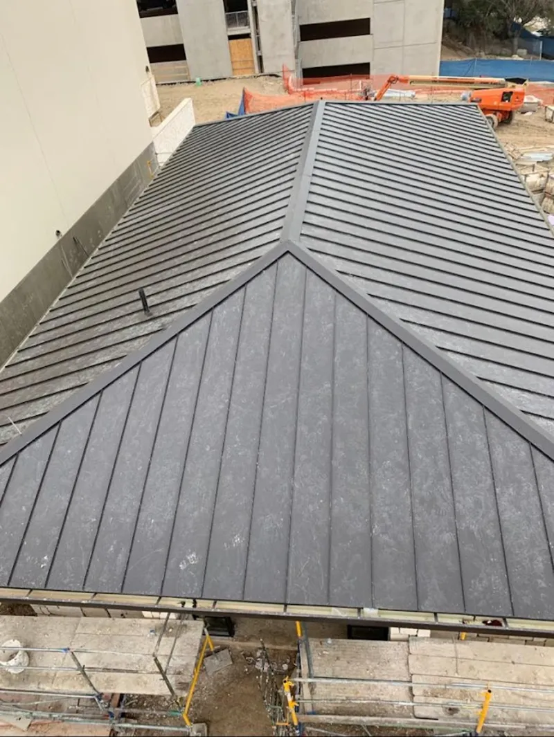 Commercial metal roof construction with crane equipment in Pelham